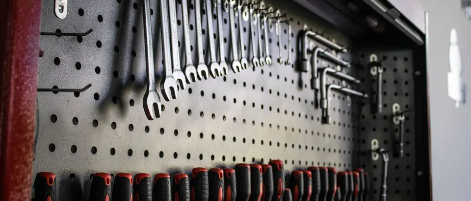 Wrenches and screwdrivers hung on a pegboard in a workshop