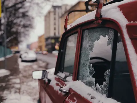 A door window broken out of a parked car in snow