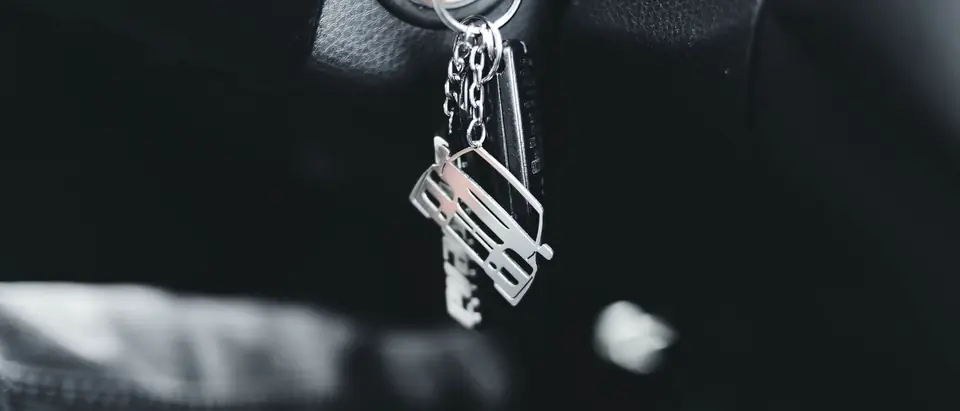A car key hanging in the ignition, in black and white