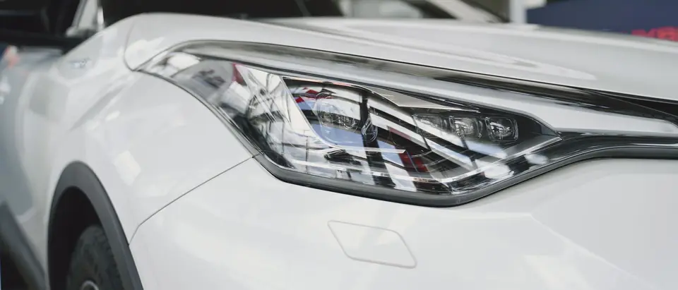 The front bumper and headlight of a modern white car