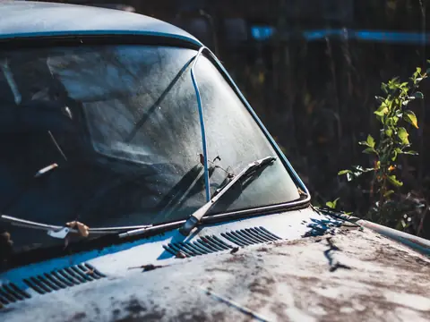 An old windshield and its wiper on a weathered car, close up